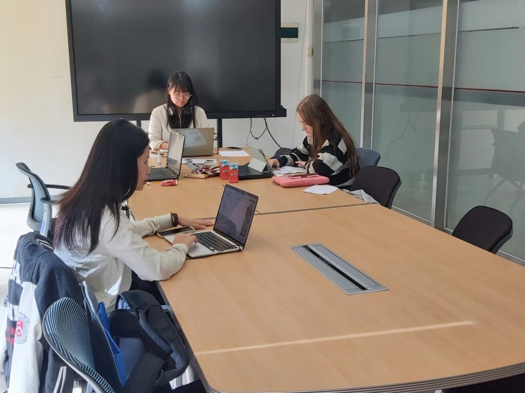 diverse office team discussing project together while learning Korean phrases on screen, modern office setting, realistic high quality photo