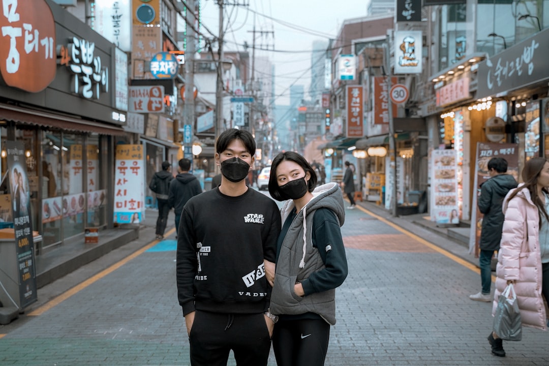 two man and woman wearing face mask in between building