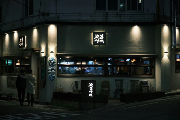family writing Hangul characters in Korean restaurant, festive mood, realistic high quality photo