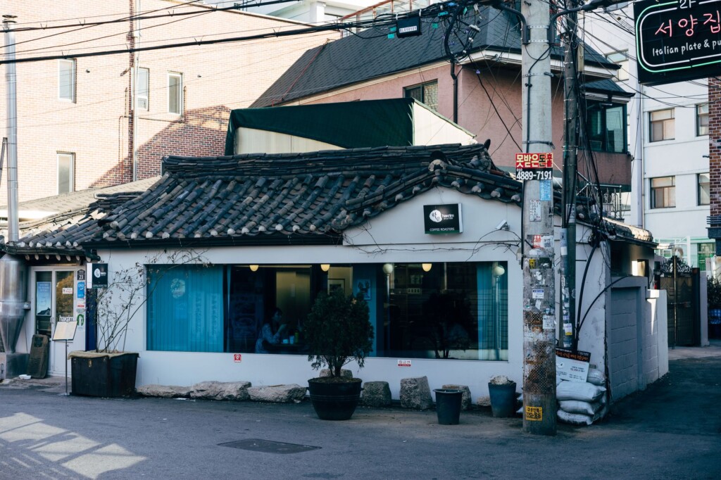 Two young Korean adults practicing Korean conversation in a warmly lit Seoul cafe