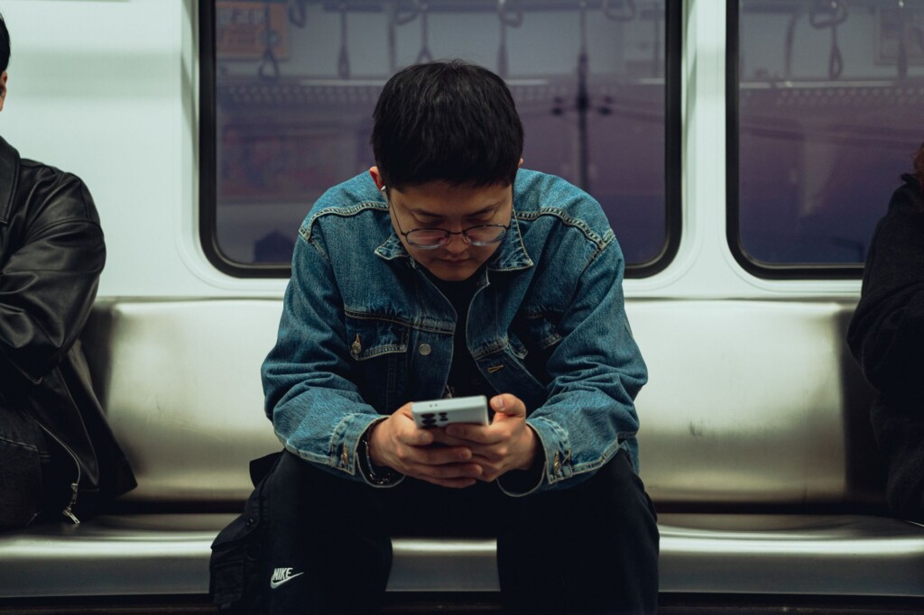 Two Korean commuters looking at a phone with cautious expressions on a subway platform