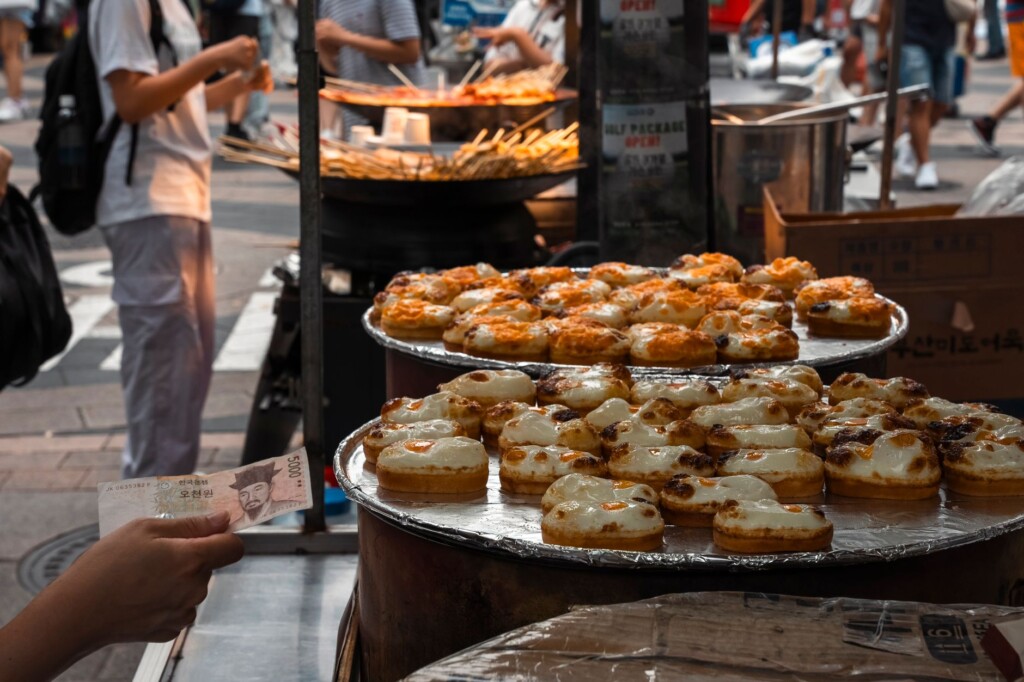 An older Korean woman and a Korean teenage boy chatting at a Seoul street food stall