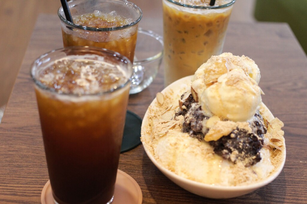 A Korean teenage boy and young woman laughing together over coffee in a café