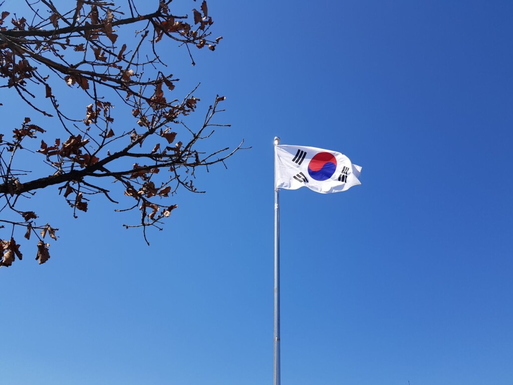 The Korean national flag waving against a clear blue summer sky