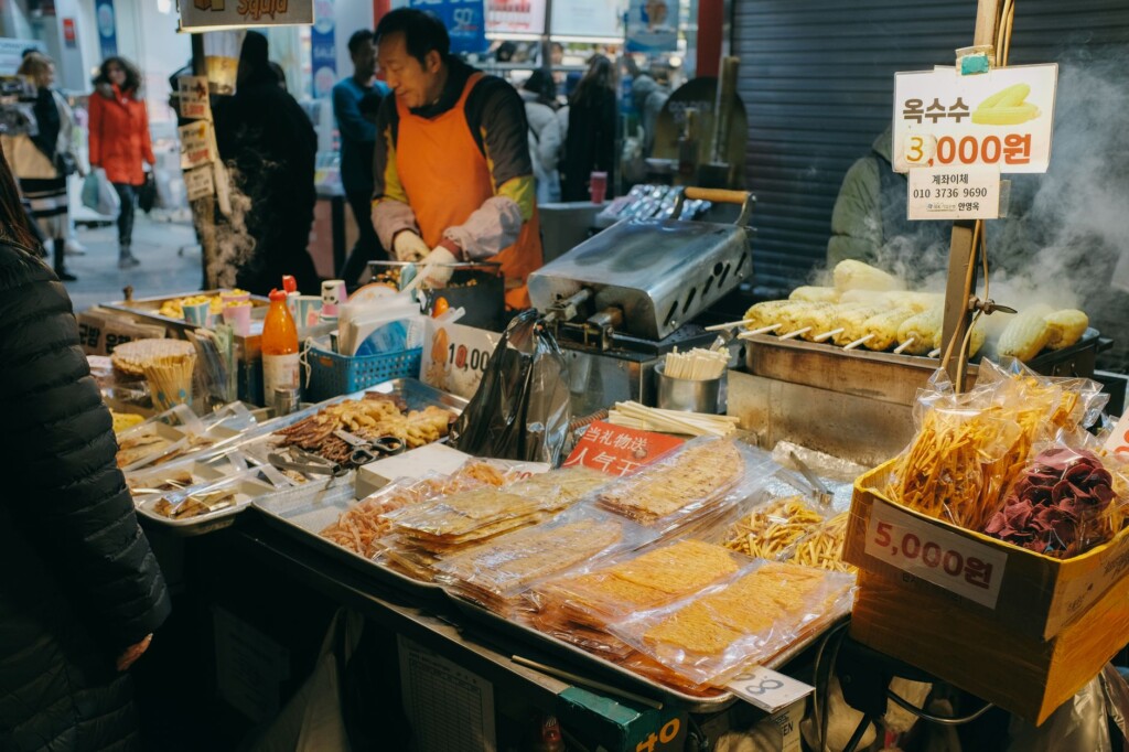 An older Korean man and a young Korean woman laughing at a night market food stall