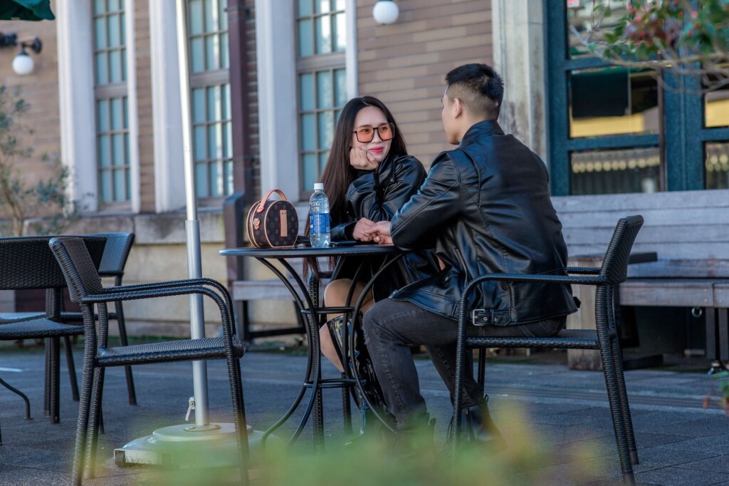 An older Korean woman and a teenage boy chatting warmly over coffee in a cafe