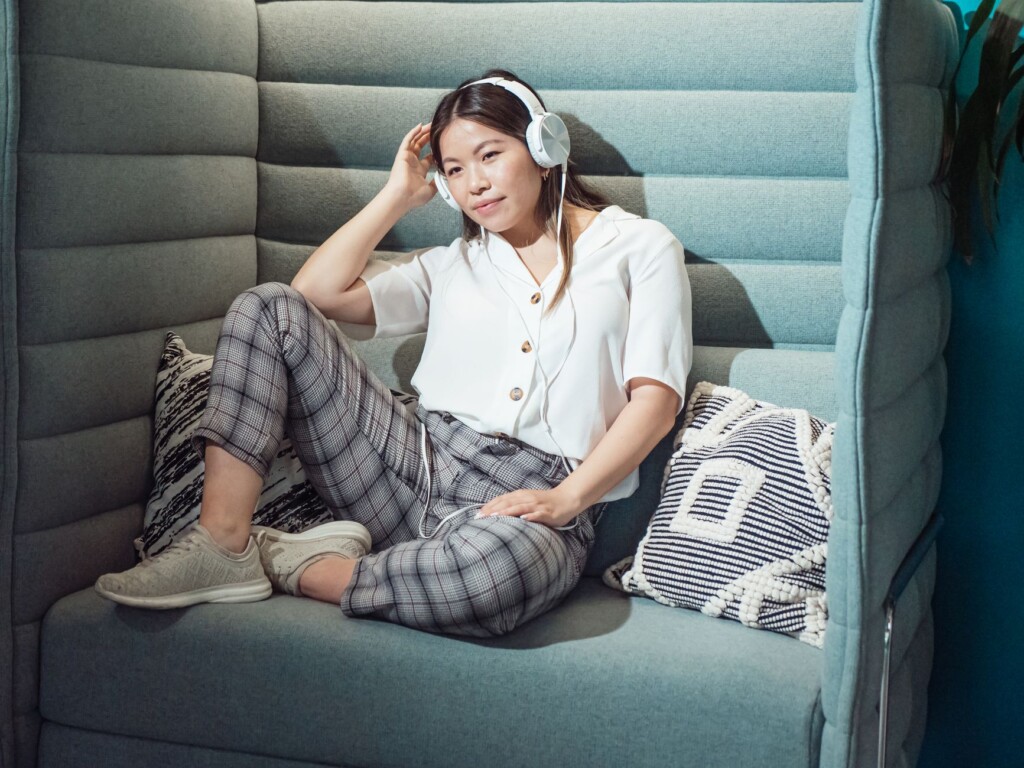A young Korean woman leaning in and listening intently on a couch at night