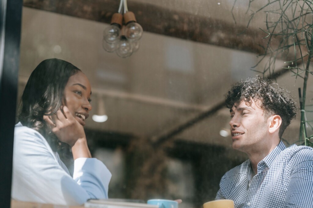 Two young Korean friends chatting happily over coffee in a cafe