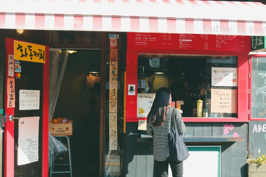Young Korean woman smiling and speaking at a warmly lit Seoul cafe counter