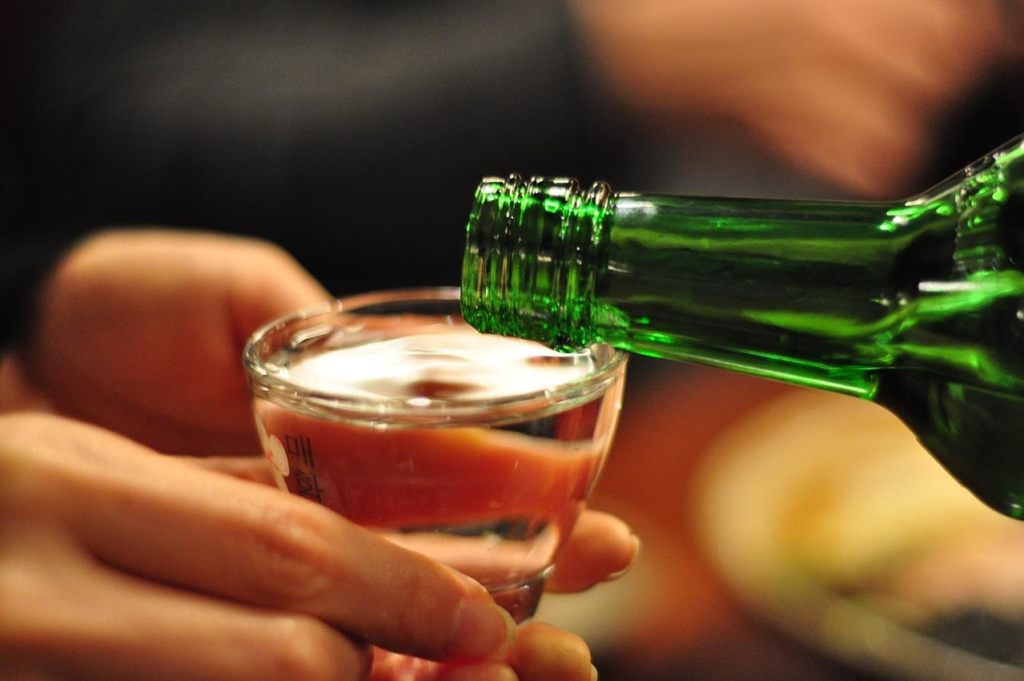 A chilled green soju bottle beside two small glasses